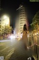 A naked woman standing on the side of a street at night.