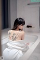 A woman sitting in a bathtub with a tattoo on her back.