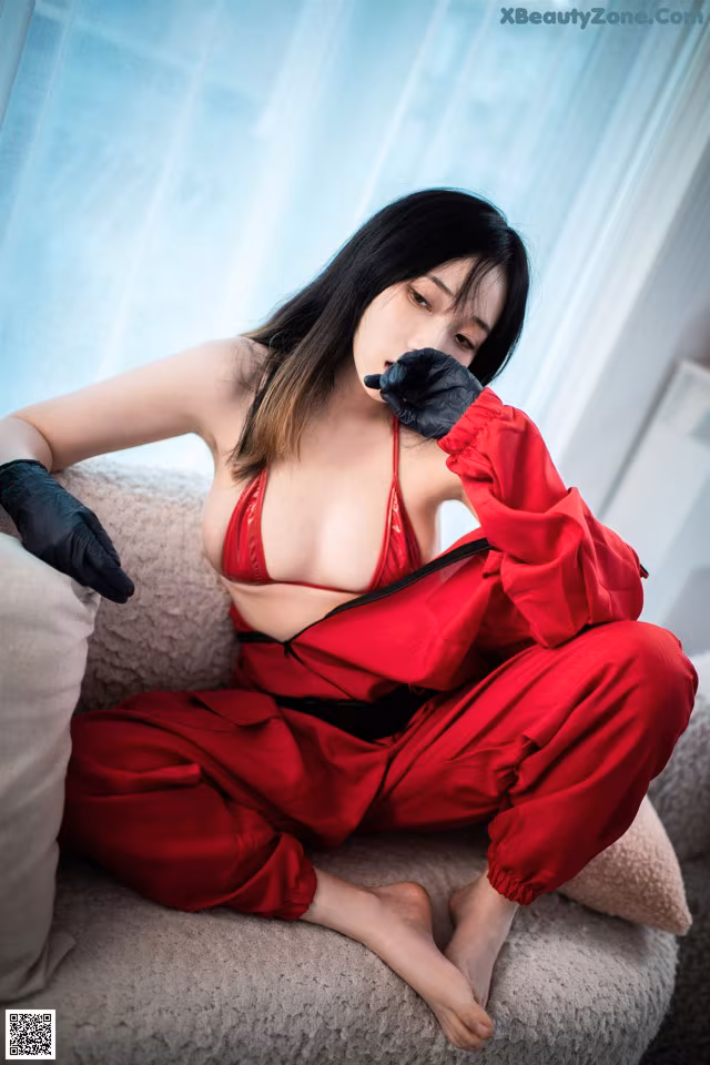 A woman in a red dress sitting on a couch.