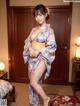 A woman in a blue kimono posing in a hotel room.