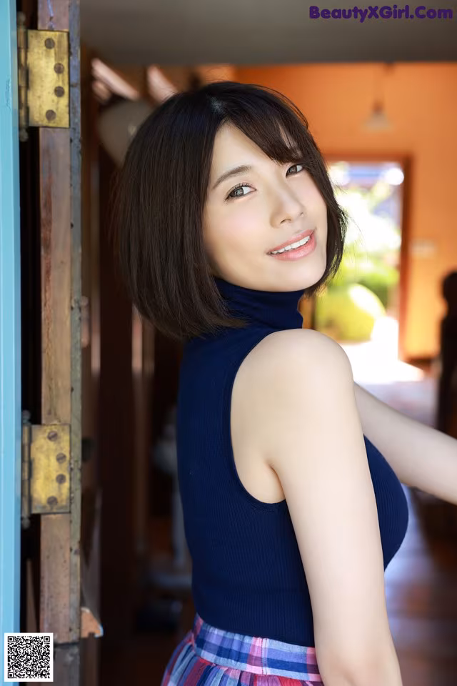 A woman in a blue top and plaid skirt posing for a picture.