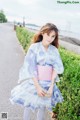 A woman in a blue and pink kimono is posing for a picture.