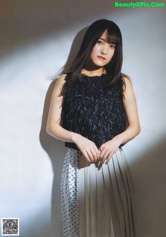 A woman standing in front of a white wall.