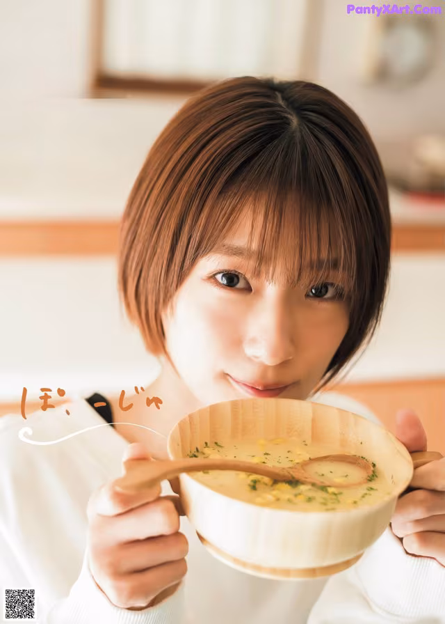 A woman holding a bowl of soup with a wooden spoon.