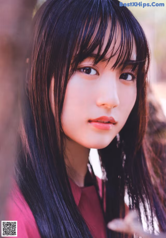 A woman with long black hair and bangs is posing for a picture.