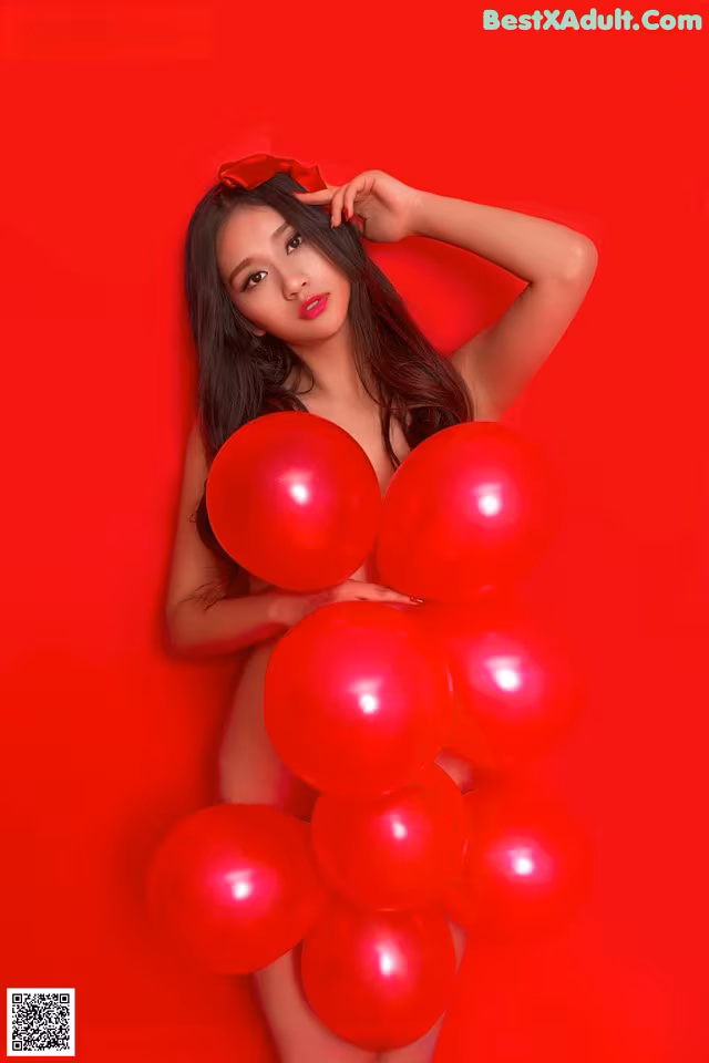 A woman holding a bunch of red balloons.