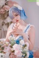 A woman in a blue and white dress holding a bouquet of flowers.