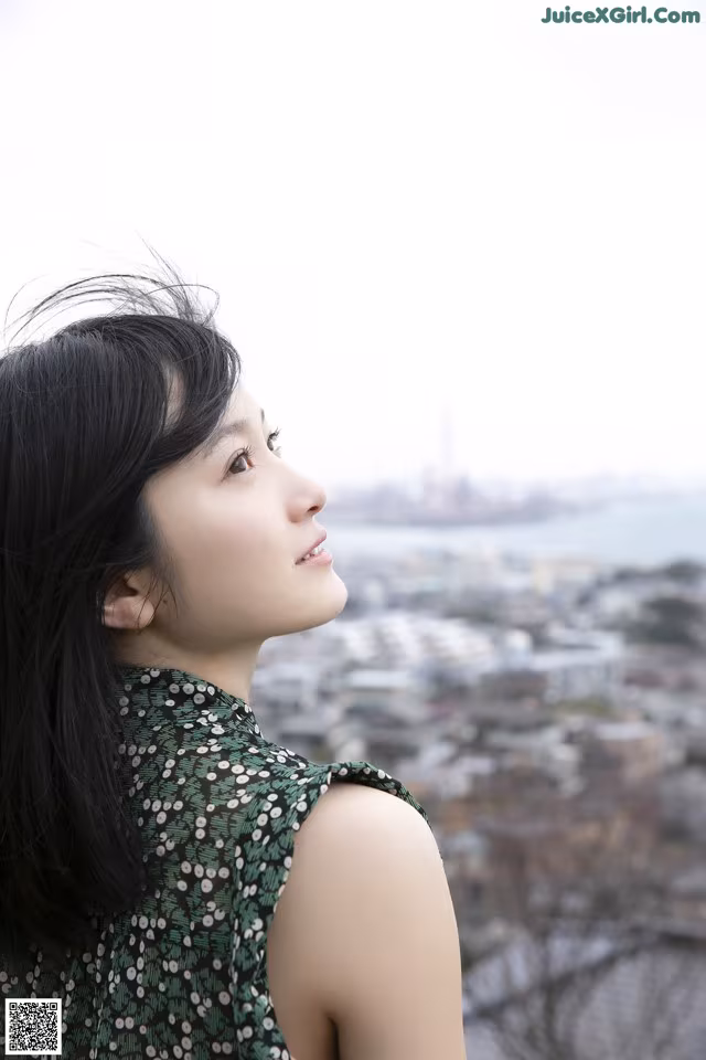 A woman in a green dress looking out over a city.
