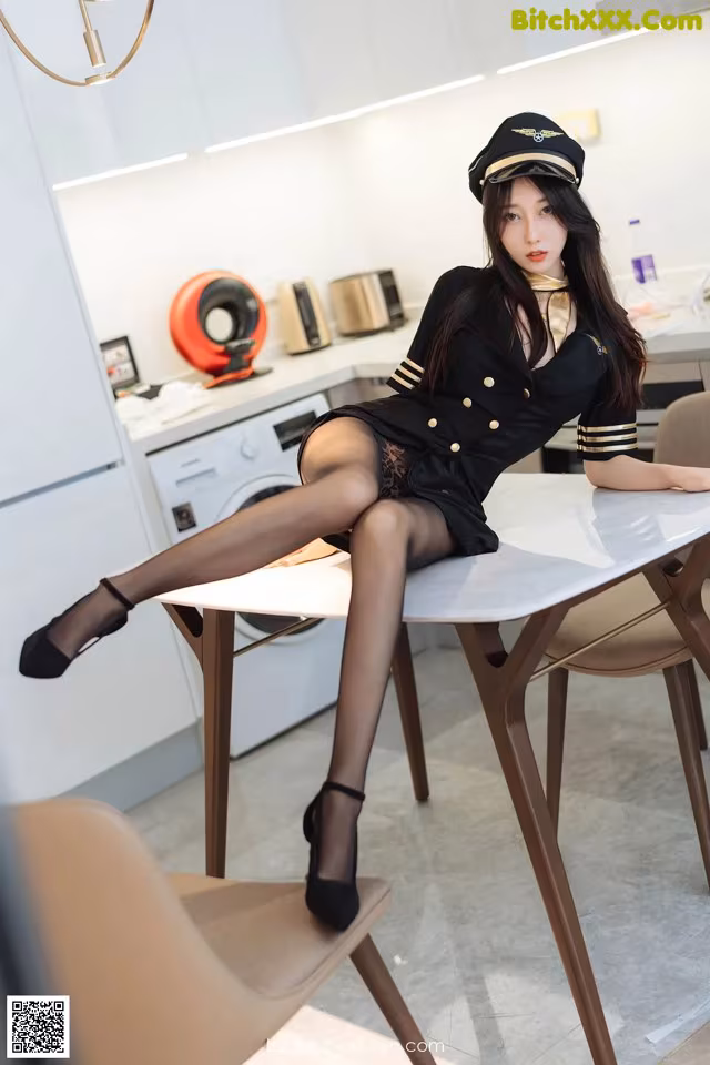 A woman sitting at a table in a kitchen.