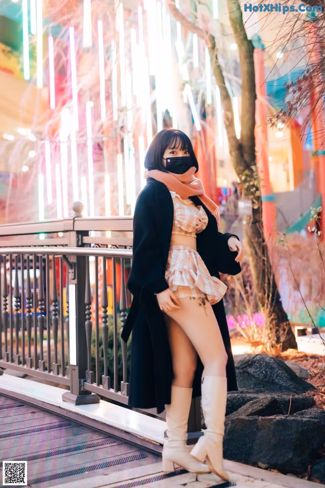 A woman wearing a face mask standing on a bridge.