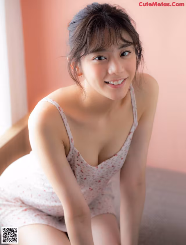 A woman in a white dress sitting on a bed.
