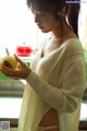 A woman in a white sweater holding an apple.