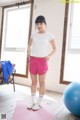 A woman standing on a yoga mat in a room.