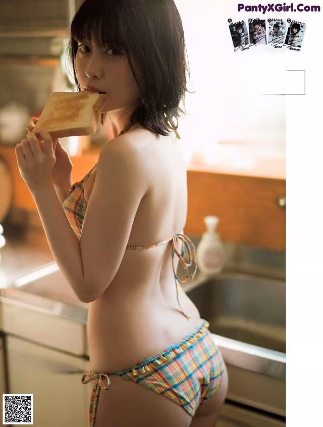 A woman in a bikini eating a piece of bread.