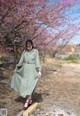 A woman in a green dress standing in front of a flowering tree.