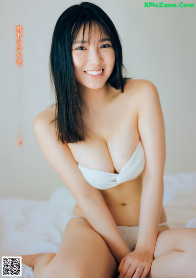 A woman in a white bikini sitting on a bed.