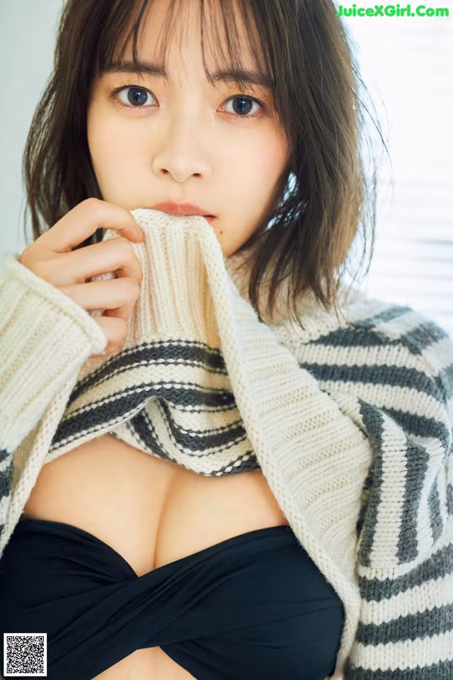 A woman in a black bikini top and a striped sweater.
