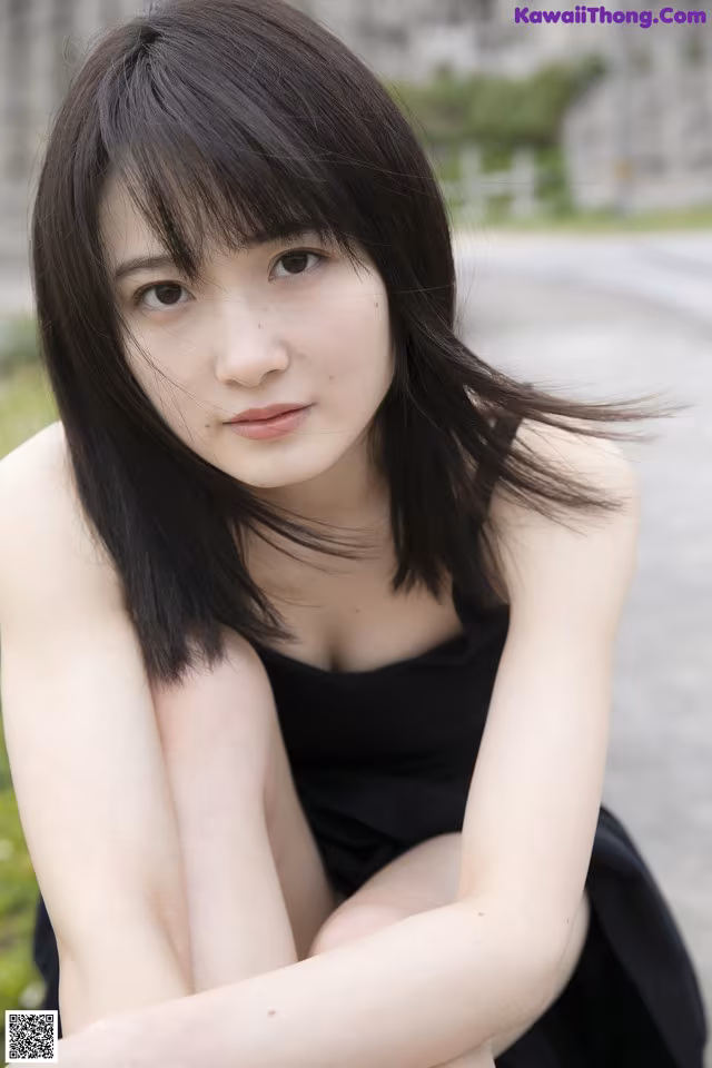 A woman in a black dress sitting on the ground.