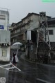 A woman holding an umbrella standing in the middle of a street.