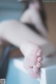 A woman sitting on top of a bathtub with her feet up.