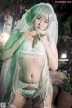 A woman with long white hair wearing a green lingerie.