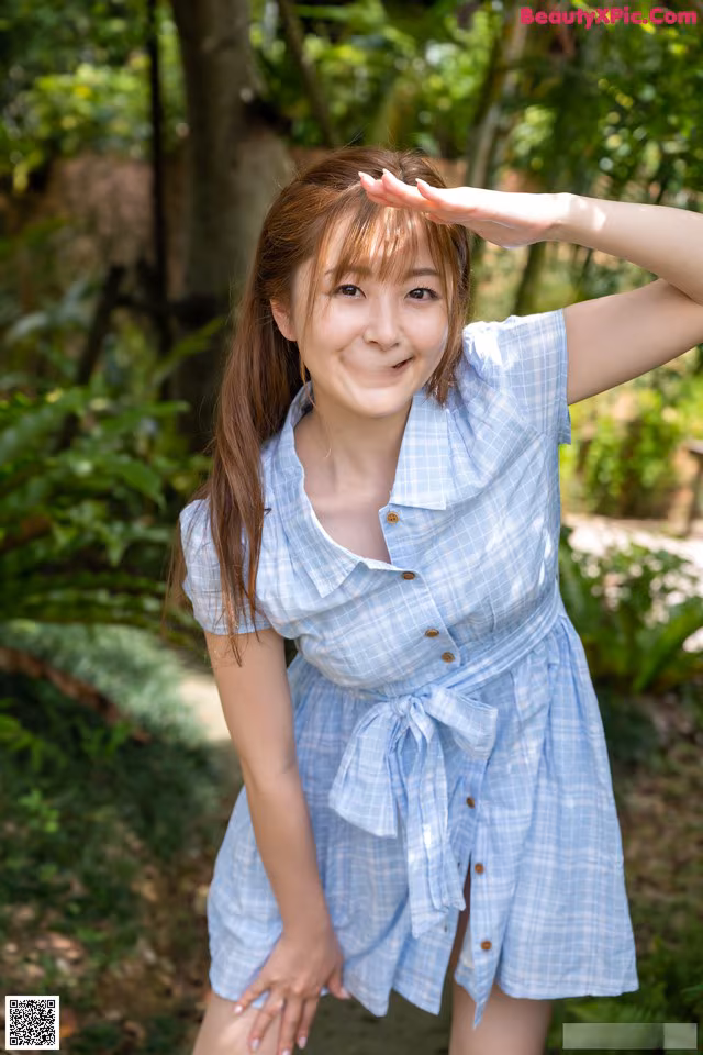 A woman in a blue and white checkered shirt posing for a picture.